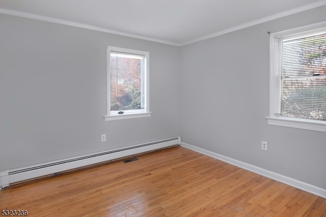 spare room with light wood-type flooring, a baseboard heating unit, and ornamental molding