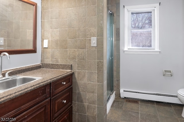 bathroom featuring baseboard heating, vanity, toilet, and a shower with shower door