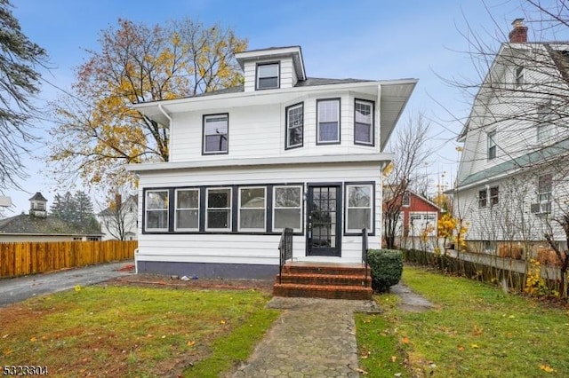 american foursquare style home with fence and a front lawn