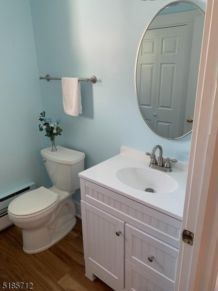 bathroom featuring baseboard heating, wood-type flooring, toilet, and vanity