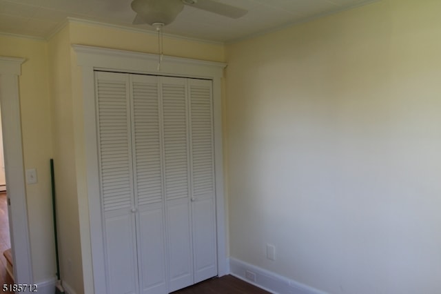 unfurnished bedroom featuring ceiling fan, crown molding, dark hardwood / wood-style floors, and a closet