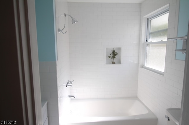 bathroom featuring tiled shower / bath, a healthy amount of sunlight, and toilet