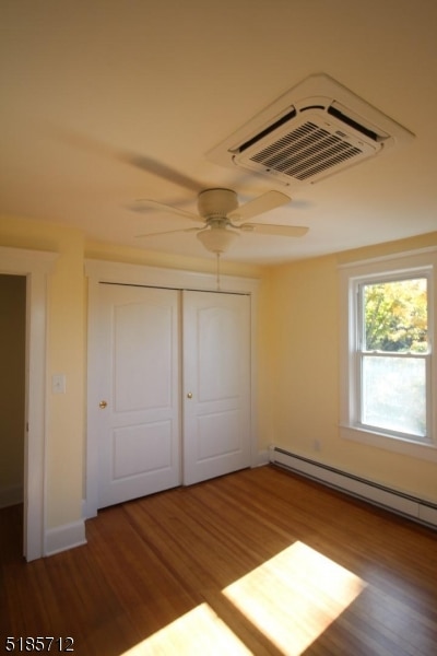 unfurnished bedroom with a closet, hardwood / wood-style floors, ceiling fan, and a baseboard radiator