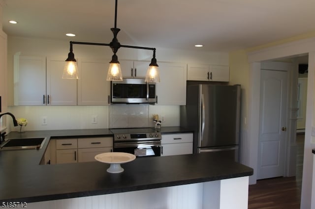 kitchen with pendant lighting, appliances with stainless steel finishes, white cabinets, and sink