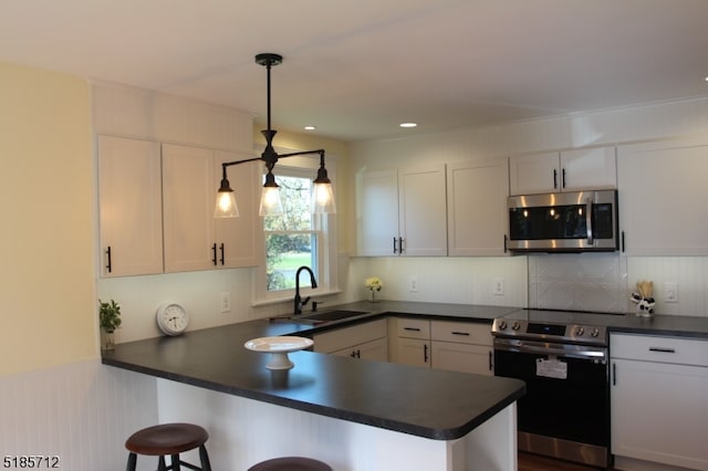 kitchen with stainless steel appliances, white cabinets, decorative light fixtures, and kitchen peninsula