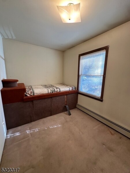 bedroom with baseboard heating and carpet