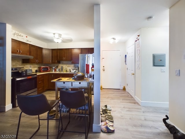 kitchen with light wood-type flooring, appliances with stainless steel finishes, decorative backsplash, and ceiling fan