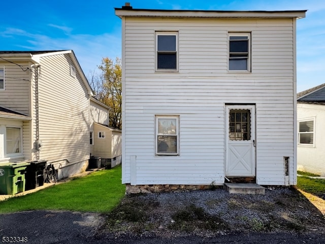 rear view of house featuring central air condition unit and a yard