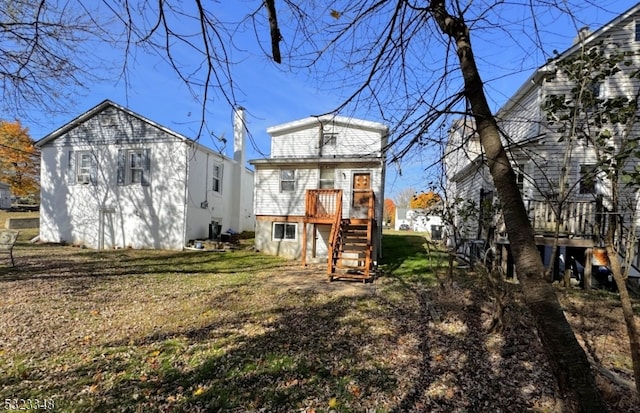 rear view of house with a lawn and a wooden deck