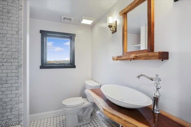 bathroom with tiled shower, sink, and toilet