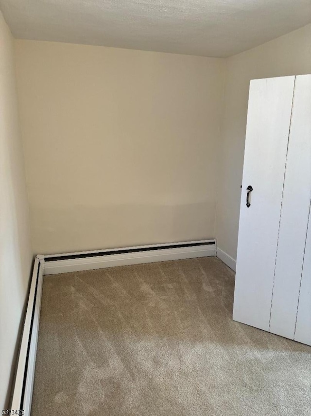 spare room with light colored carpet and baseboard heating