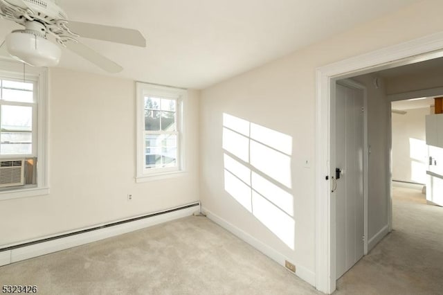 empty room with light colored carpet, baseboard heating, a healthy amount of sunlight, and ceiling fan