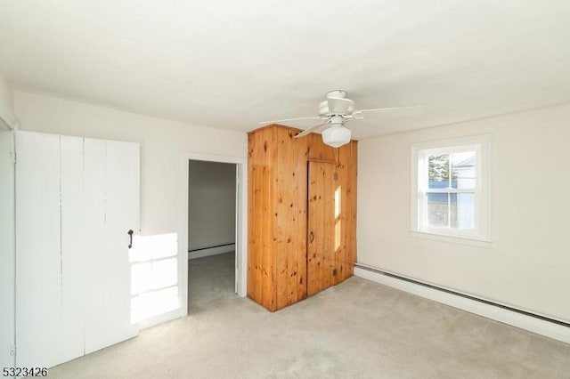 unfurnished bedroom with ceiling fan, light colored carpet, baseboard heating, and a closet