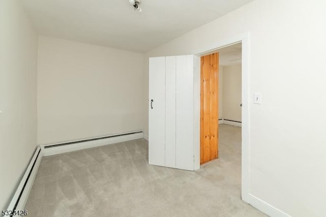 carpeted empty room featuring a baseboard heating unit