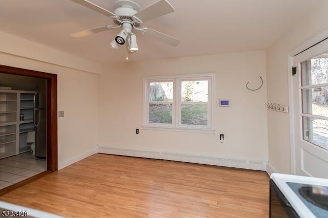 spare room with ceiling fan, light hardwood / wood-style floors, baseboard heating, and a wealth of natural light