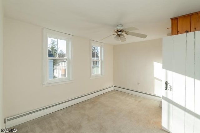 spare room with ceiling fan, light colored carpet, and a baseboard heating unit