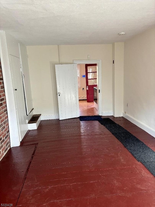 empty room with hardwood / wood-style floors, a textured ceiling, and a baseboard heating unit