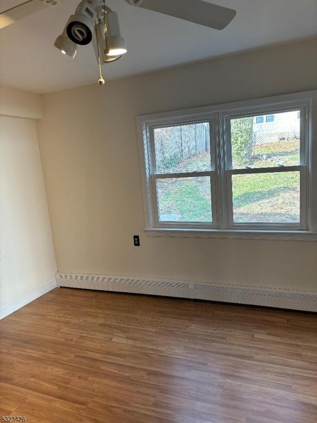 spare room with ceiling fan, a baseboard radiator, and hardwood / wood-style flooring