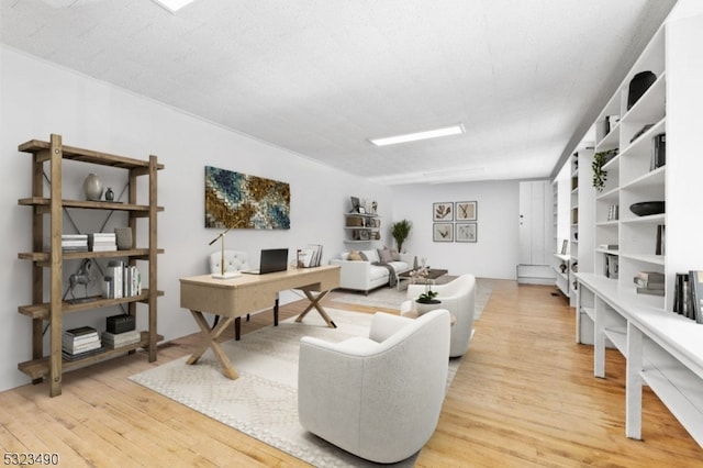 home office featuring light hardwood / wood-style floors and a textured ceiling