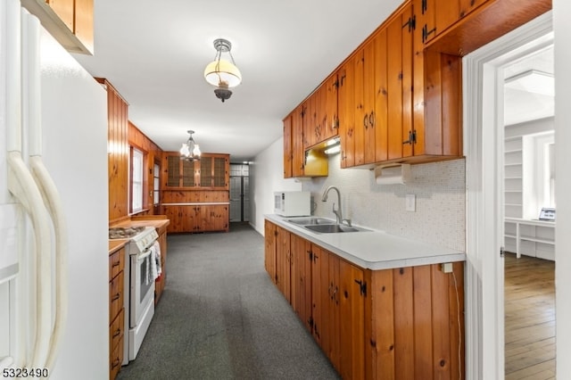 kitchen featuring dark wood-type flooring, sink, backsplash, pendant lighting, and white appliances