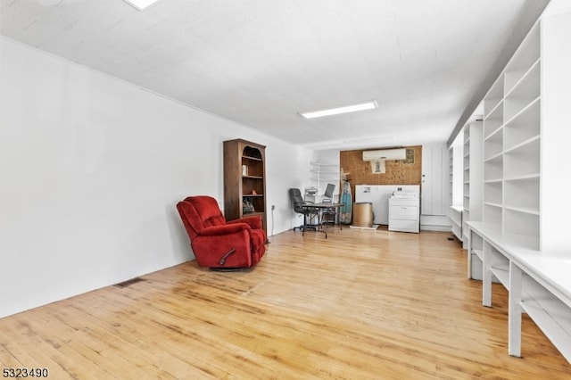 living area with wood-type flooring, an AC wall unit, and washer / dryer