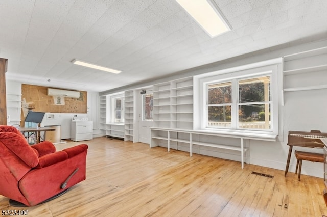 living room with a wall mounted AC, hardwood / wood-style floors, and washer and clothes dryer