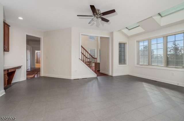 unfurnished living room featuring ceiling fan, tile patterned flooring, and lofted ceiling with skylight