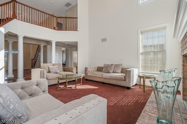 living room featuring carpet flooring, decorative columns, and a towering ceiling