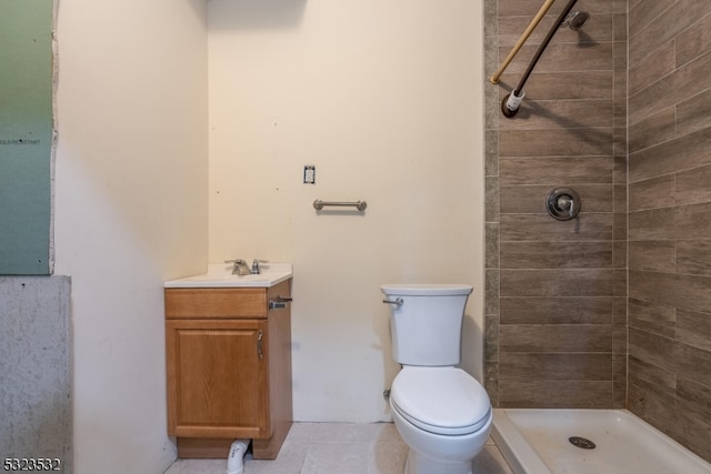 bathroom featuring tiled shower, tile patterned floors, vanity, and toilet