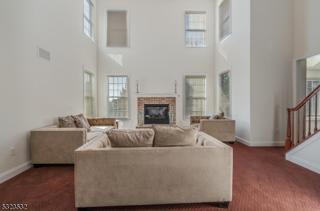 carpeted living room featuring a fireplace and a high ceiling