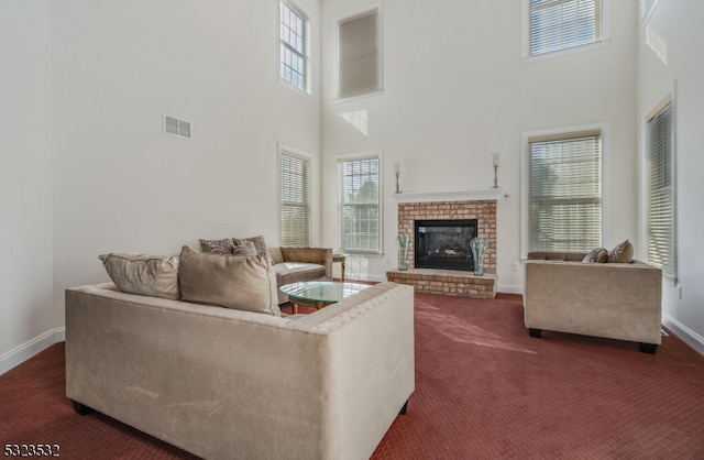 carpeted living room with a high ceiling, a wealth of natural light, and a brick fireplace