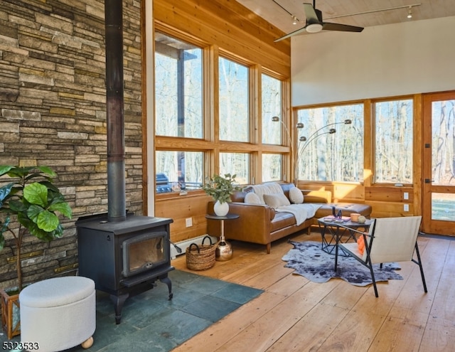 sunroom featuring ceiling fan and a wood stove