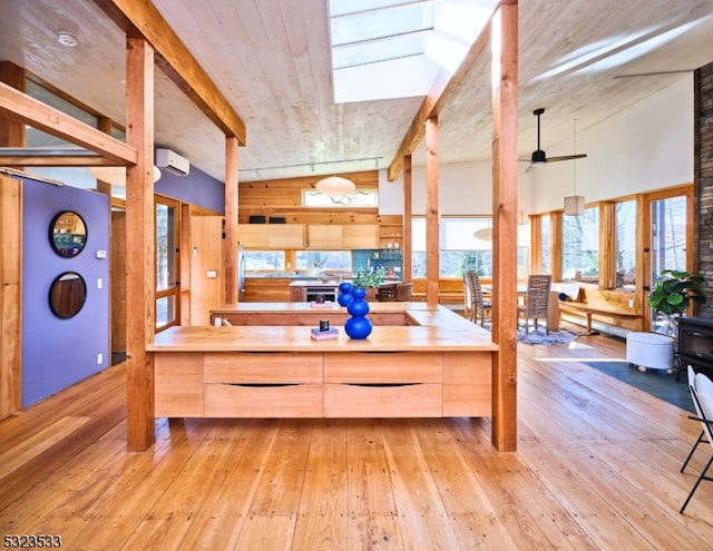 kitchen with wood counters, light brown cabinetry, a skylight, ceiling fan, and light hardwood / wood-style flooring