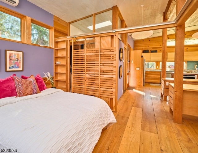 bedroom featuring stainless steel fridge and light hardwood / wood-style floors