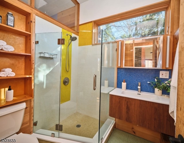 bathroom with decorative backsplash, a shower with door, vanity, and toilet