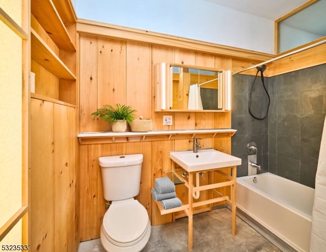 bathroom with tiled shower / bath combo, wood walls, toilet, and concrete floors