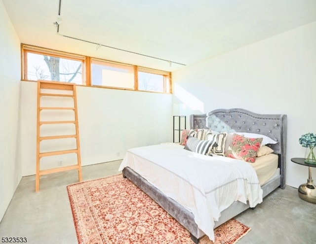 bedroom featuring concrete floors and track lighting