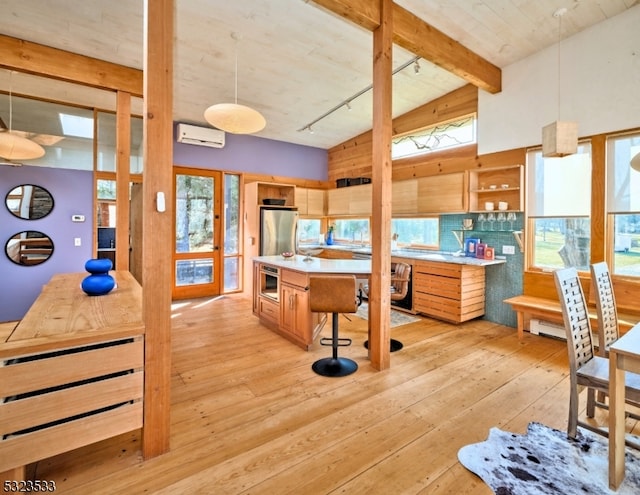 kitchen featuring appliances with stainless steel finishes, light wood-type flooring, an AC wall unit, and pendant lighting