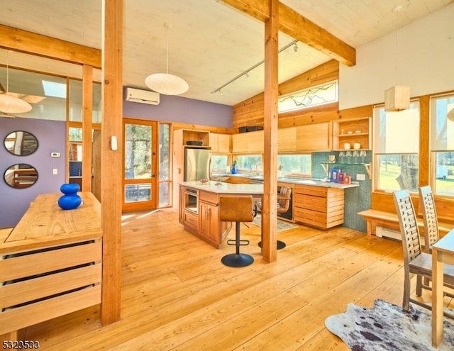 kitchen featuring lofted ceiling with beams, light hardwood / wood-style floors, a healthy amount of sunlight, and appliances with stainless steel finishes