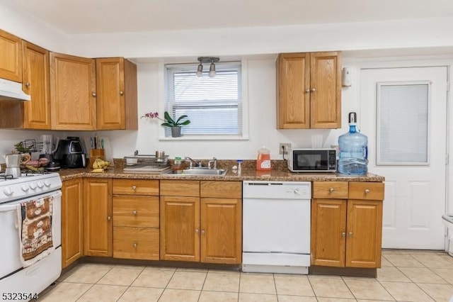 kitchen with white appliances, sink, light tile patterned floors, and dark stone counters