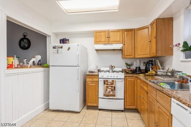 kitchen featuring light stone countertops, light tile patterned floors, white appliances, and sink