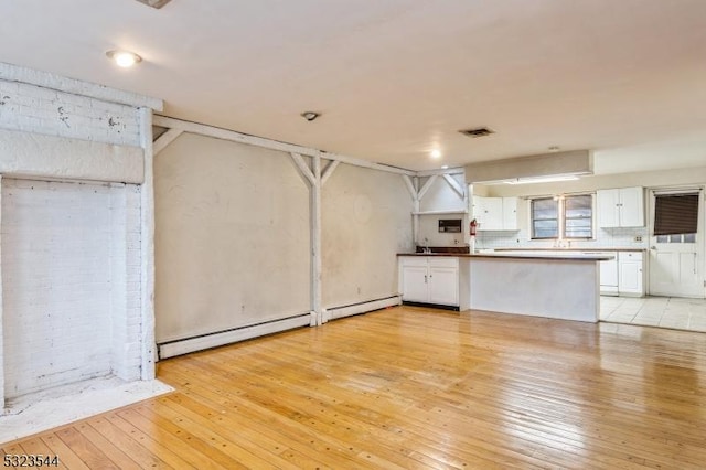 kitchen featuring white cabinets, kitchen peninsula, baseboard heating, and light hardwood / wood-style flooring