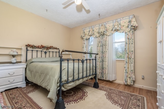 bedroom with wood-type flooring, ceiling fan, and a textured ceiling