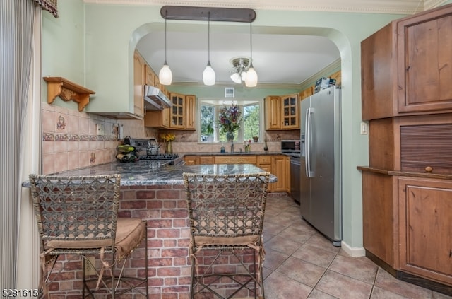 kitchen with pendant lighting, kitchen peninsula, stainless steel appliances, and tasteful backsplash