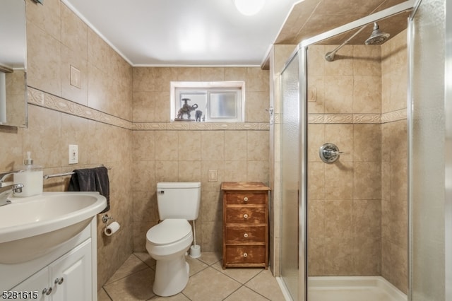 bathroom with tile patterned flooring, vanity, a shower with shower door, toilet, and tile walls