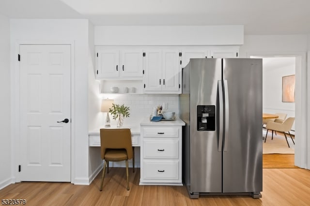 kitchen with white cabinets, stainless steel fridge with ice dispenser, light hardwood / wood-style flooring, and decorative backsplash