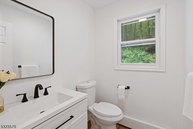 bathroom featuring toilet, vanity, and a baseboard radiator