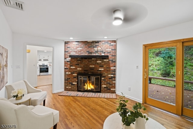 living room with hardwood / wood-style floors, a fireplace, and ceiling fan