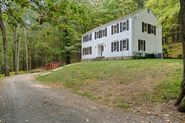 colonial house with a front yard and a storage shed