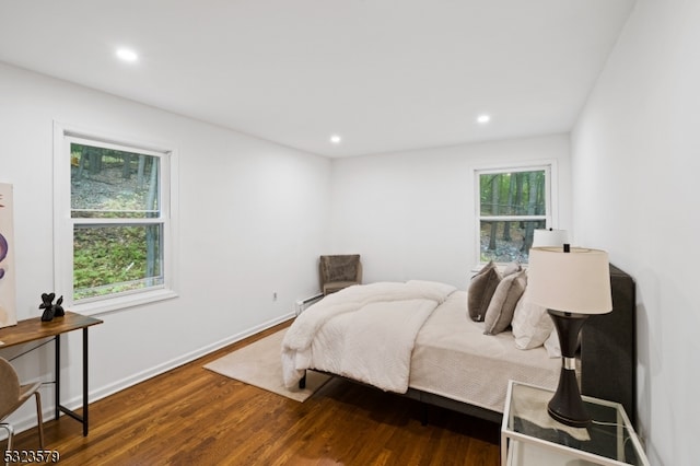 bedroom featuring hardwood / wood-style flooring, a baseboard radiator, and multiple windows